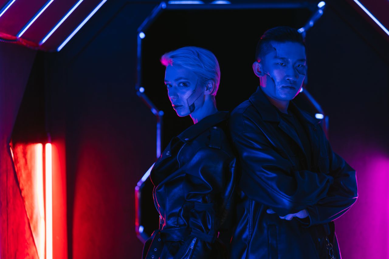 A man and woman in cyberpunk style with neon lighting, showcasing futuristic fashion.
